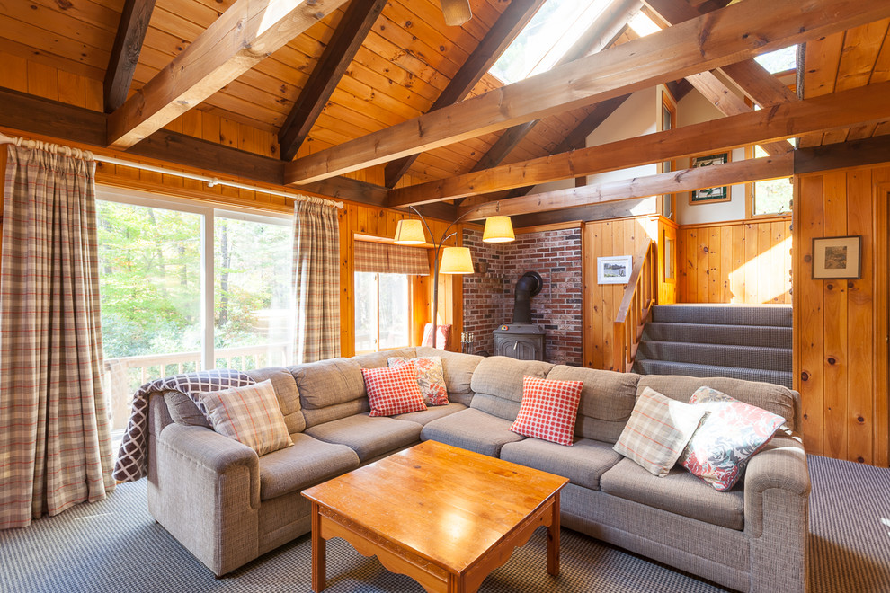 Inspiration pour une salle de séjour chalet avec moquette, un poêle à bois et un manteau de cheminée en brique.