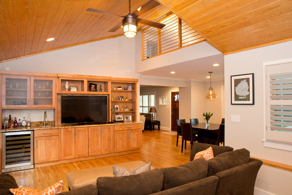 Exemple d'une salle de séjour chic de taille moyenne et ouverte avec un bar de salon, un mur gris, un sol en bois brun et un téléviseur indépendant.