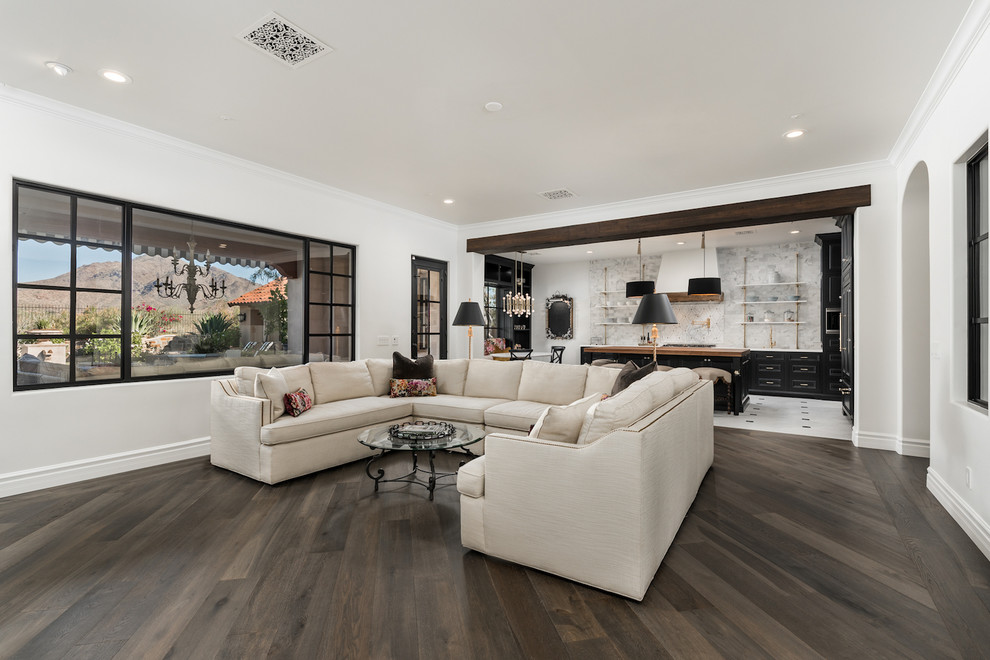 Photo of an expansive mediterranean open plan games room in Phoenix with a home bar, white walls, dark hardwood flooring, a standard fireplace, a stone fireplace surround, a wall mounted tv and brown floors.