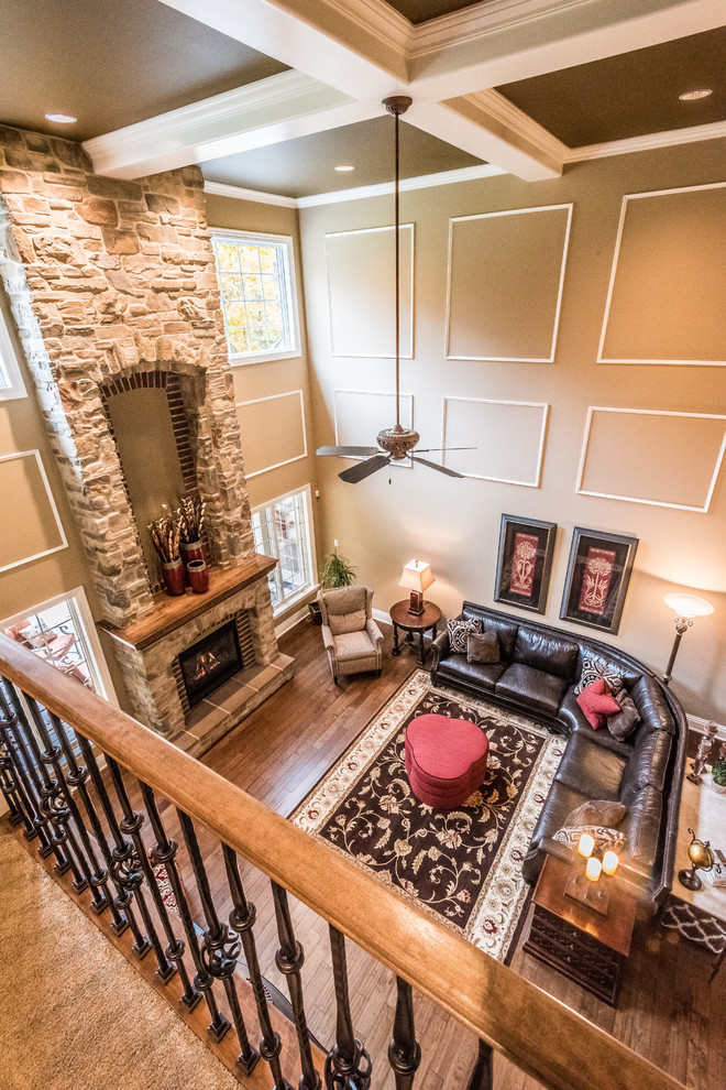 Cette image montre une salle de séjour traditionnelle avec un sol en bois brun, une cheminée standard, un manteau de cheminée en pierre et un téléviseur fixé au mur.