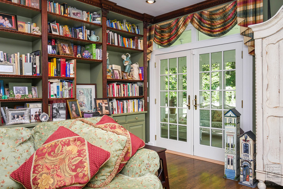 Cette photo montre une salle de séjour de taille moyenne et fermée avec une bibliothèque ou un coin lecture, un mur vert, parquet foncé et un sol marron.
