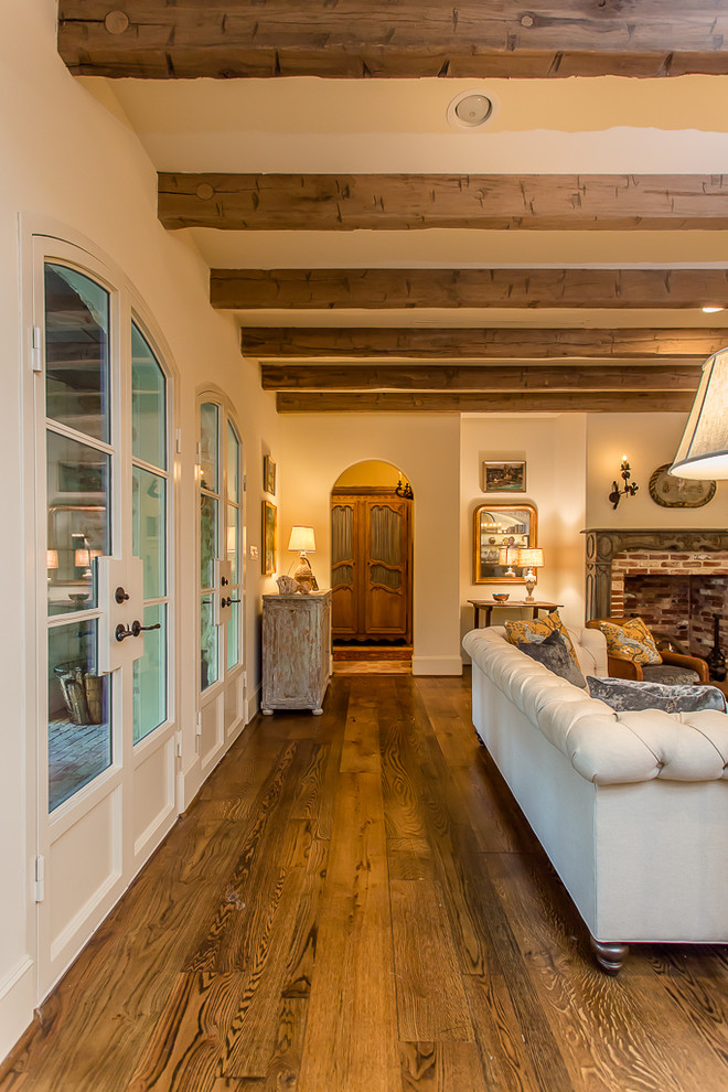 Idée de décoration pour une grande salle de séjour méditerranéenne ouverte avec un mur beige, un sol en bois brun, une cheminée standard, un manteau de cheminée en bois et un téléviseur fixé au mur.