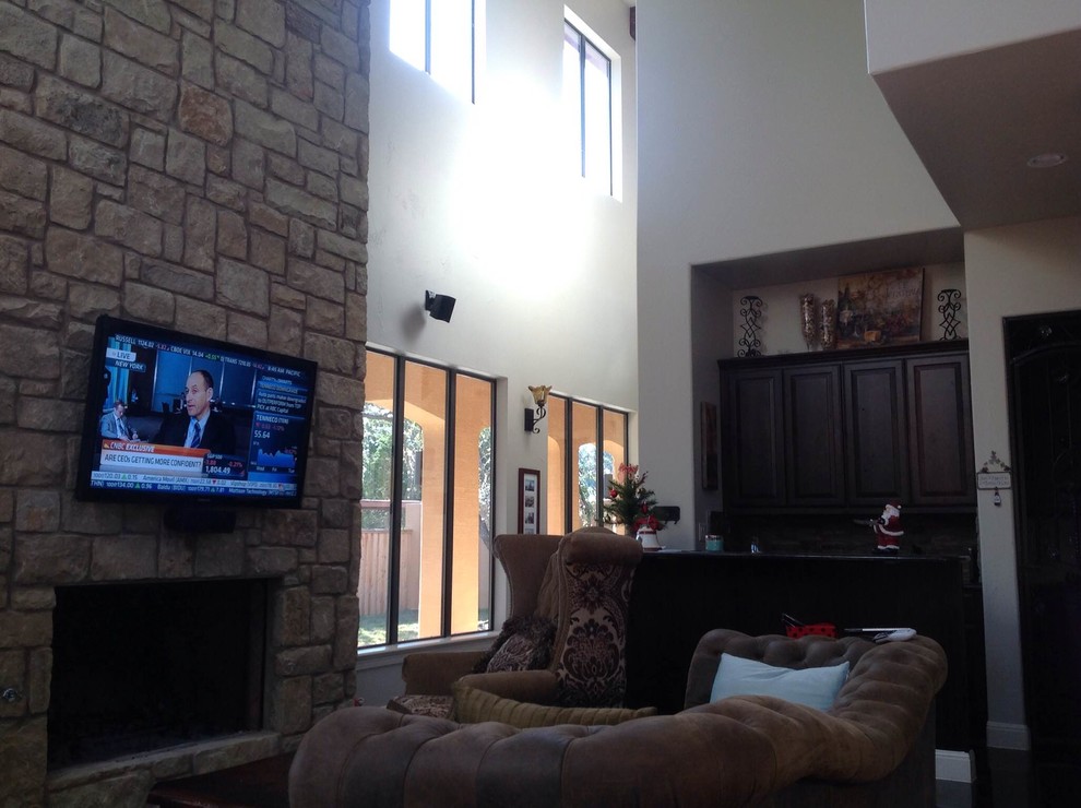 Mittelgroßes, Offenes Klassisches Wohnzimmer mit beiger Wandfarbe, Betonboden, Kamin, Kaminumrandung aus Stein und TV-Wand in Austin