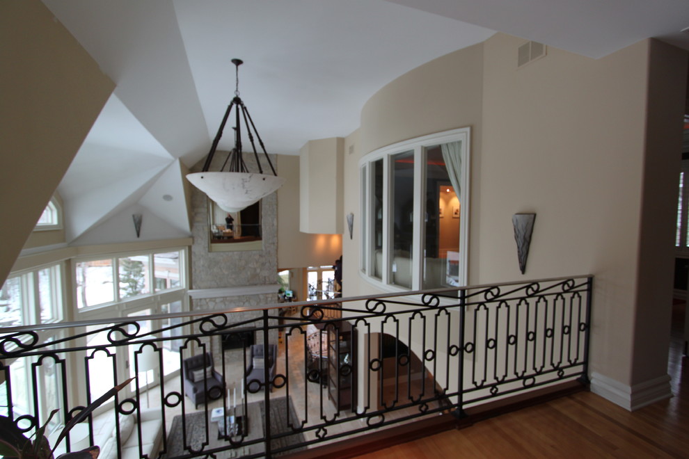 На фото: большая двухуровневая гостиная комната в стиле неоклассика (современная классика) с фасадом камина из камня