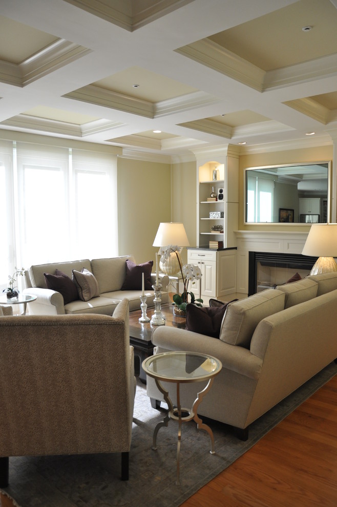 Imagen de sala de estar abierta clásica renovada grande con televisor colgado en la pared, paredes amarillas, suelo de madera clara, todas las chimeneas y marco de chimenea de madera