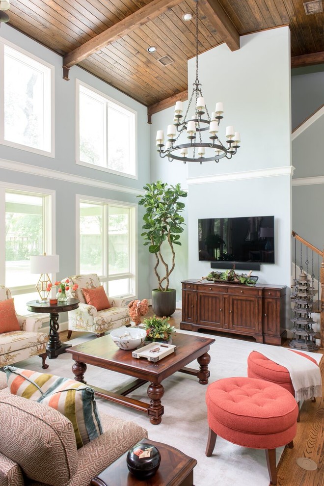 Foto de sala de estar tipo loft tradicional grande sin chimenea con paredes azules, suelo de madera en tonos medios y televisor colgado en la pared