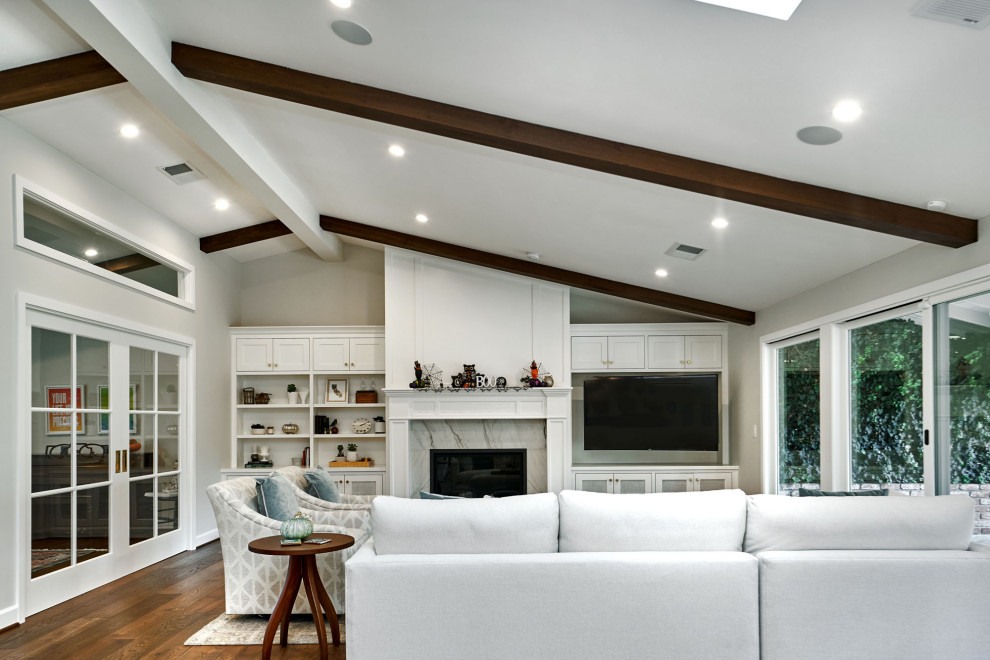 Design ideas for a large classic open plan games room in San Francisco with grey walls, medium hardwood flooring, a standard fireplace, a stone fireplace surround, a built-in media unit, brown floors and a vaulted ceiling.