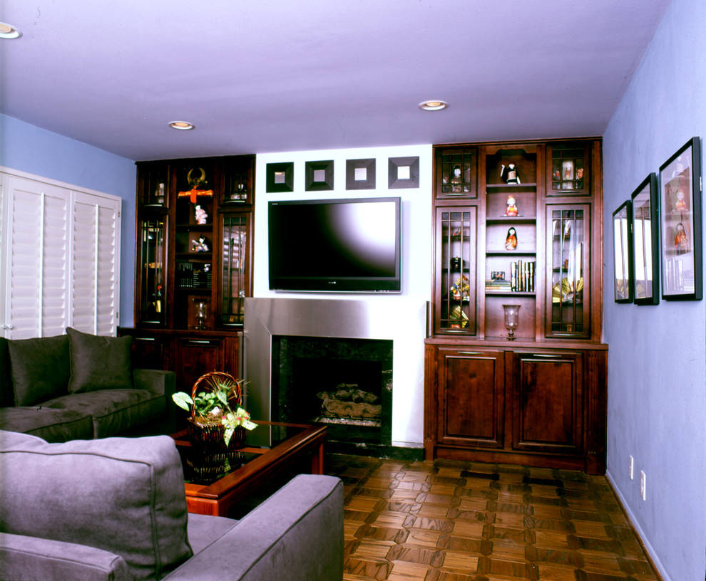 Modelo de sala de estar abierta de estilo zen de tamaño medio con paredes grises, suelo de madera en tonos medios, todas las chimeneas, marco de chimenea de metal y televisor colgado en la pared