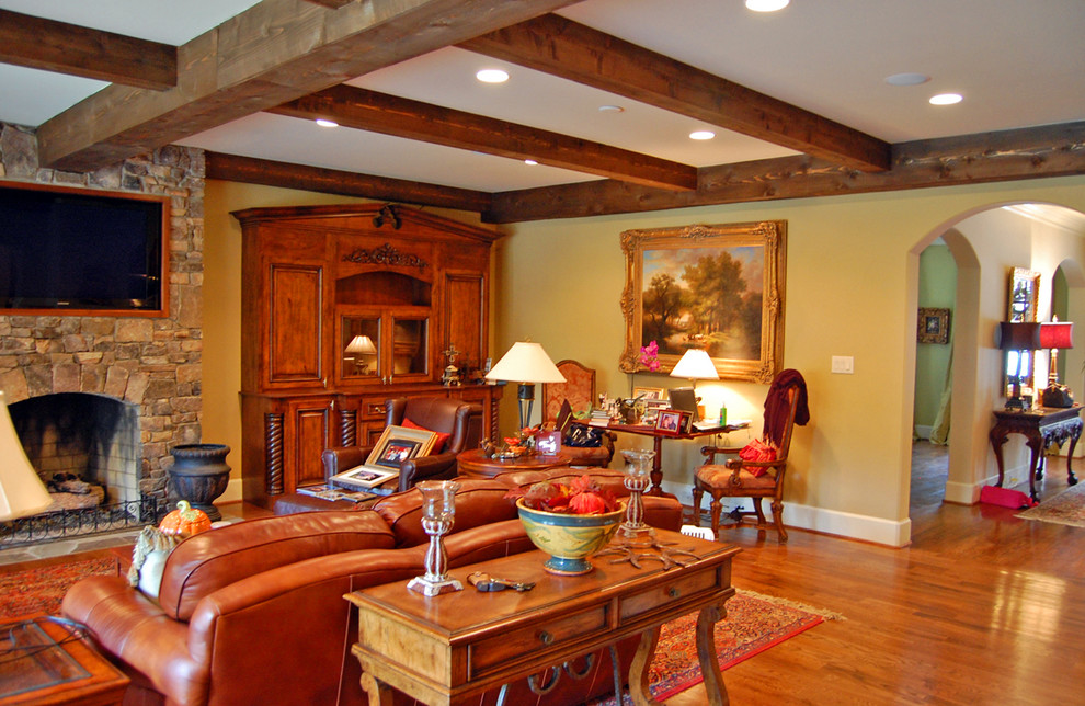 Imagen de sala de estar con barra de bar abierta rústica grande con suelo de madera en tonos medios, todas las chimeneas, marco de chimenea de piedra y televisor colgado en la pared