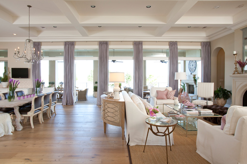 Diseño de sala de estar abierta tradicional con paredes beige, suelo de madera en tonos medios y televisor colgado en la pared