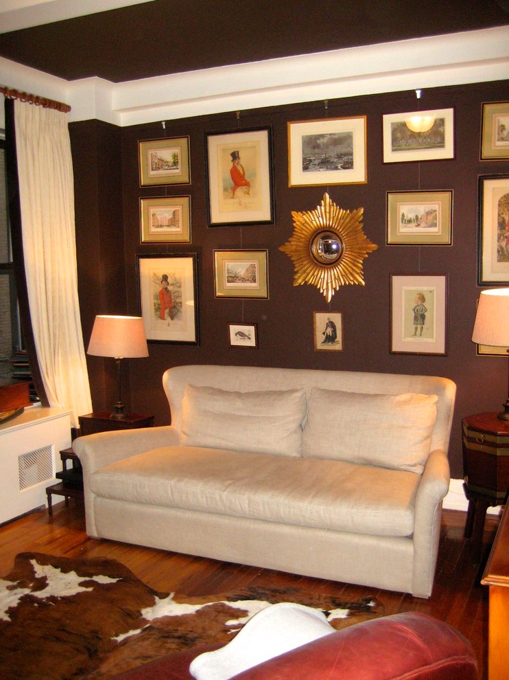 This is an example of a classic enclosed games room in New York with a reading nook, brown walls and dark hardwood flooring.