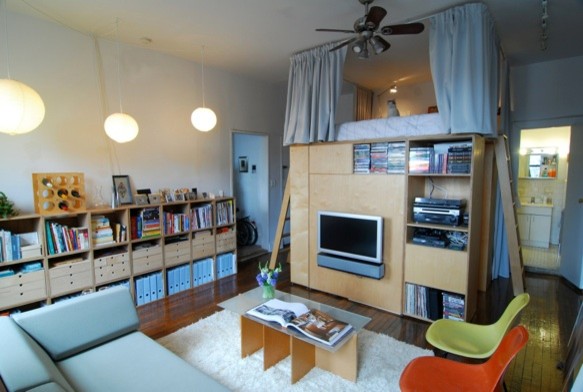 Foto på ett litet funkis allrum på loftet, med en väggmonterad TV, ett bibliotek, vita väggar och mörkt trägolv