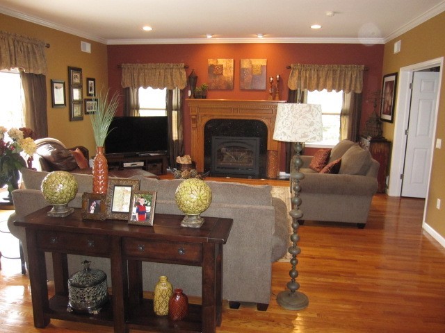 Imagen de sala de estar abierta clásica renovada de tamaño medio con paredes rojas, suelo de madera en tonos medios, todas las chimeneas y televisor en una esquina