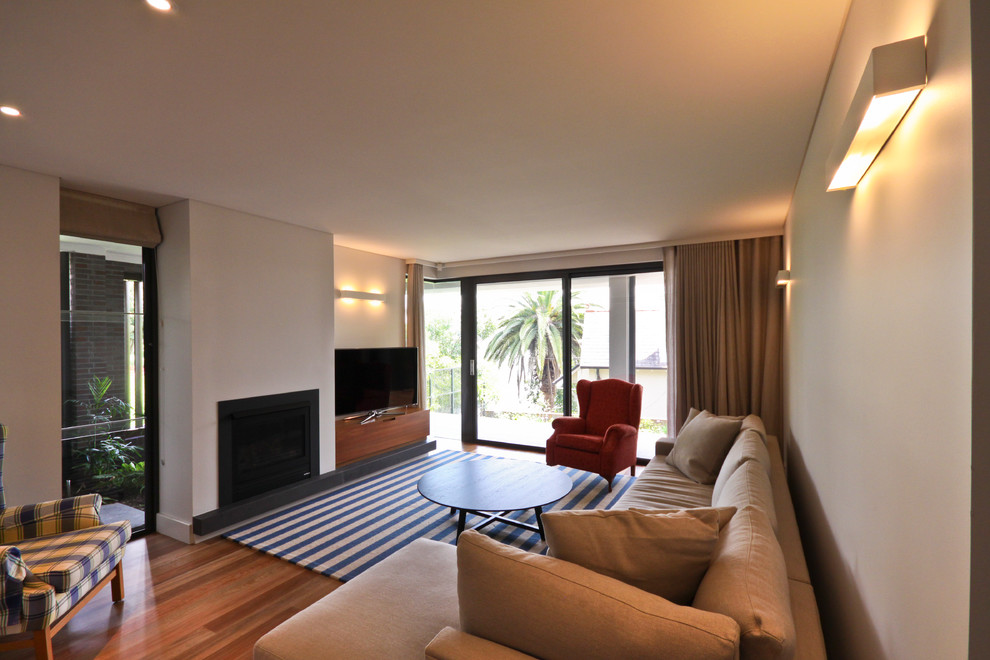 Esempio di un soggiorno contemporaneo con pareti beige, pavimento in legno massello medio, camino classico e porta TV ad angolo
