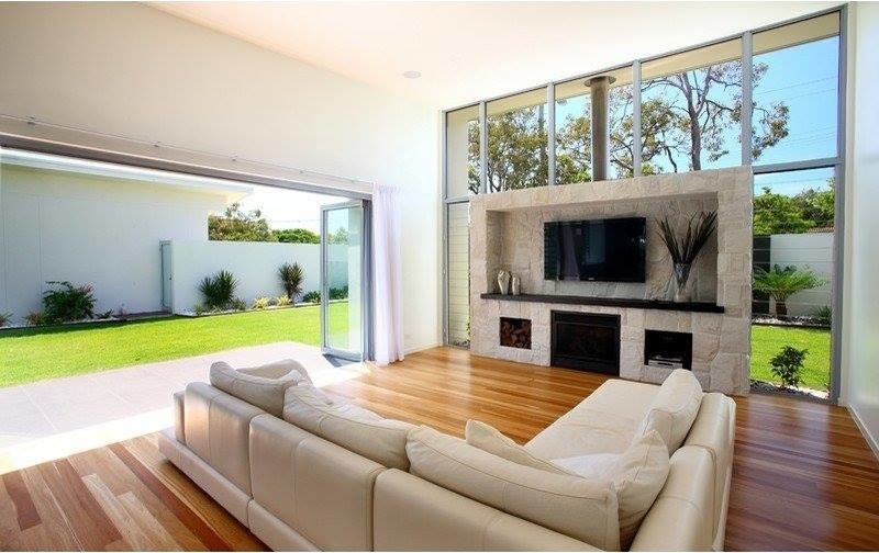 Идея дизайна: гостиная комната в современном стиле с белыми стенами, паркетным полом среднего тона, стандартным камином, фасадом камина из камня и телевизором на стене