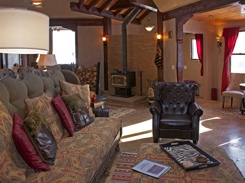 Cette image montre une salle de séjour chalet de taille moyenne et ouverte avec un mur beige, un sol en travertin, un manteau de cheminée en métal et une cheminée d'angle.