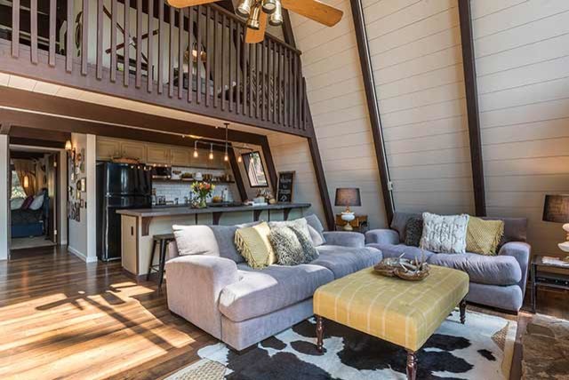 Idée de décoration pour une petite salle de séjour vintage ouverte avec un mur beige, sol en stratifié, un poêle à bois, un manteau de cheminée en métal, un téléviseur fixé au mur et un sol marron.