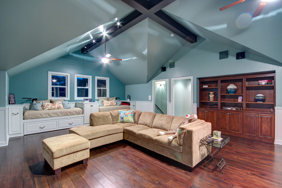 Modelo de sala de juegos en casa abierta clásica grande sin chimenea con suelo de madera en tonos medios, televisor colgado en la pared y paredes azules