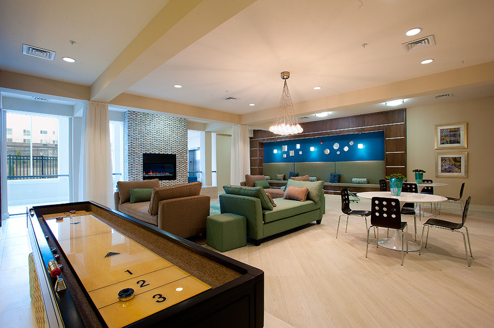 This is an example of a large contemporary open plan games room in Los Angeles with a game room, light hardwood flooring, beige walls, a standard fireplace, a tiled fireplace surround, no tv and beige floors.