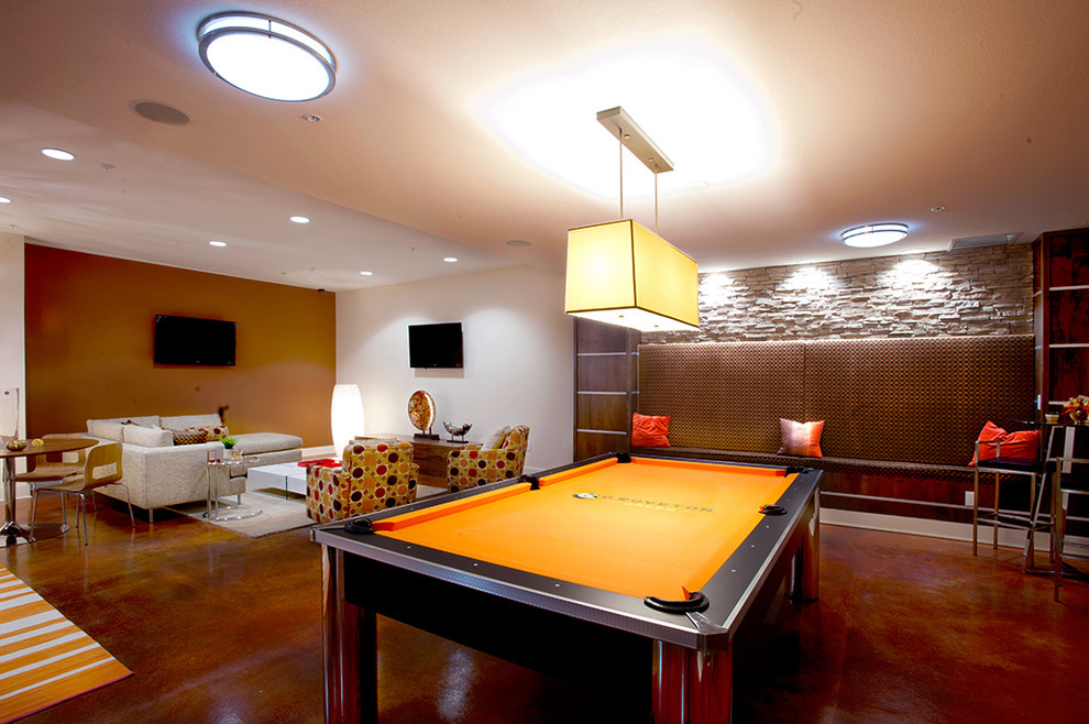 Свежая идея для дизайна: большая открытая комната для игр в современном стиле с оранжевыми стенами, бетонным полом, телевизором на стене и коричневым полом без камина - отличное фото интерьера