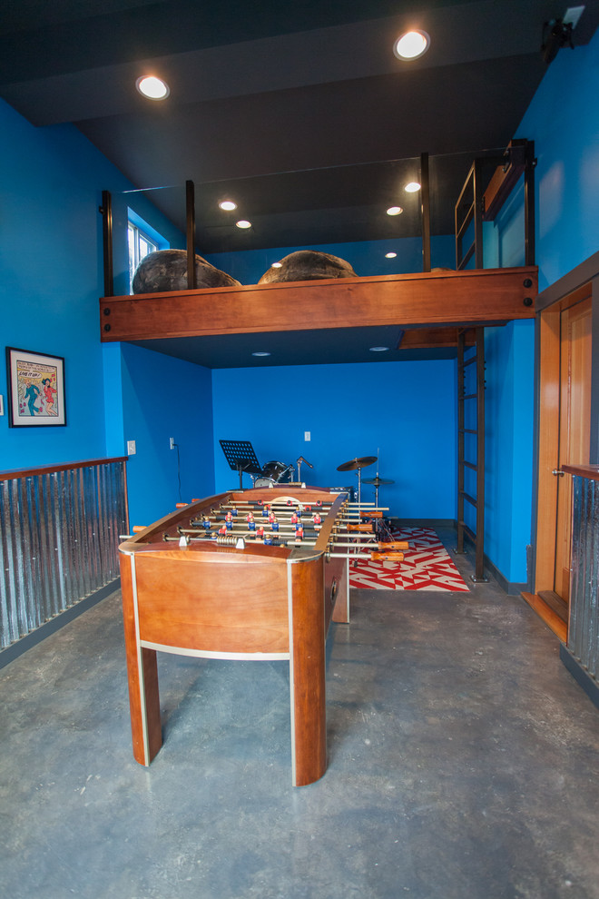 シアトルにある中くらいなインダストリアルスタイルのおしゃれな独立型ファミリールーム (ゲームルーム、青い壁、コンクリートの床、暖炉なし、壁掛け型テレビ、グレーの床) の写真