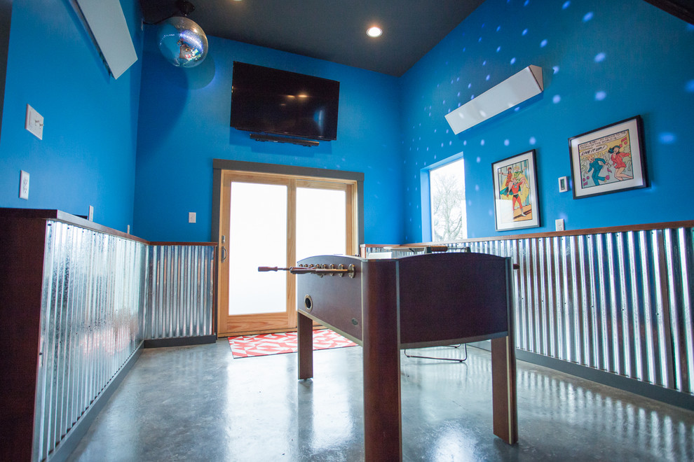 Ejemplo de sala de juegos en casa cerrada urbana de tamaño medio sin chimenea con paredes azules, suelo de cemento, televisor colgado en la pared y suelo gris