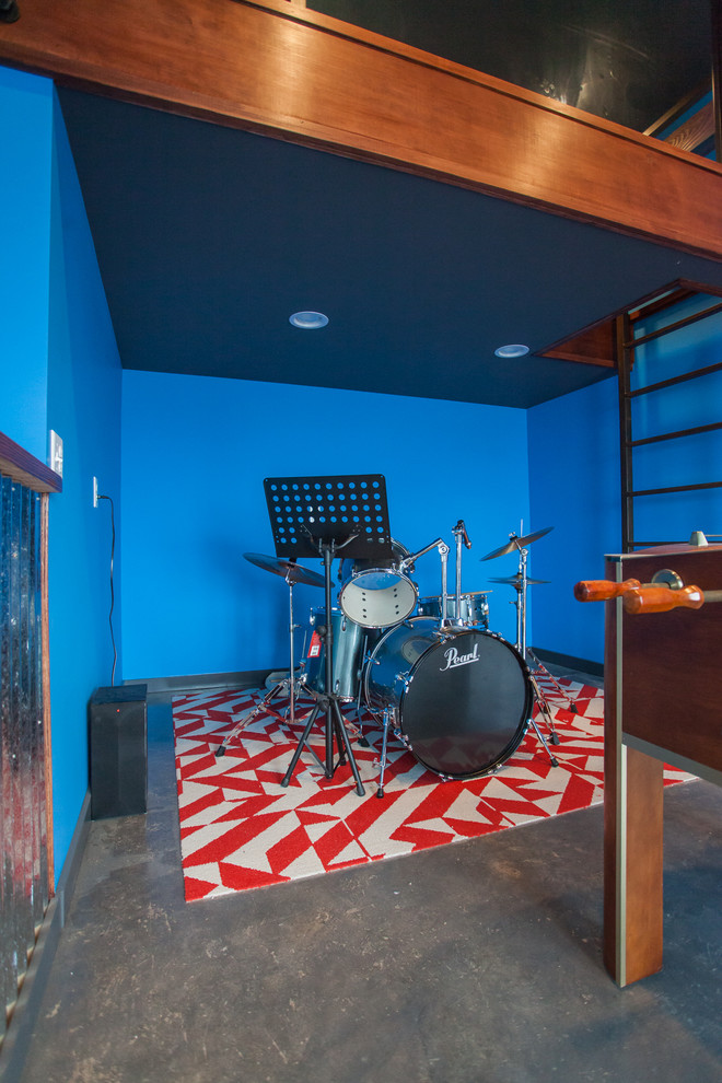 シアトルにある中くらいなインダストリアルスタイルのおしゃれな独立型ファミリールーム (ゲームルーム、青い壁、コンクリートの床、暖炉なし、壁掛け型テレビ、グレーの床) の写真