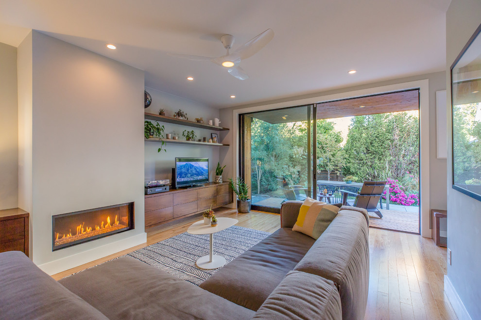 Cette image montre une petite salle de séjour minimaliste fermée avec un mur beige, parquet clair, une cheminée standard, un manteau de cheminée en plâtre et un téléviseur indépendant.