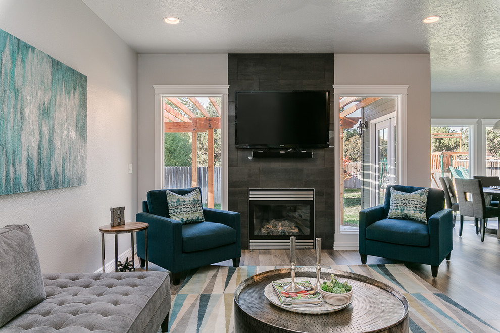 Photo of a medium sized traditional open plan games room in Boise with grey walls, vinyl flooring, a standard fireplace, a tiled fireplace surround, a wall mounted tv and grey floors.