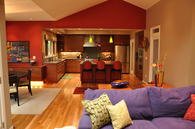 На фото: большая открытая гостиная комната в современном стиле с красными стенами и светлым паркетным полом без камина с