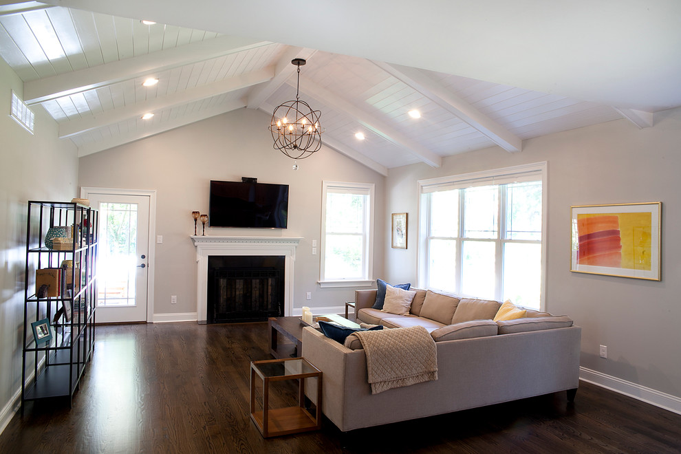 Example of a large transitional open concept dark wood floor family room design in Philadelphia with gray walls, a standard fireplace, a wood fireplace surround and a wall-mounted tv
