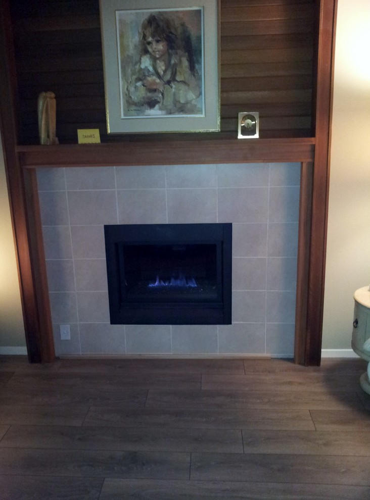 Imagen de sala de estar cerrada tradicional pequeña sin televisor con suelo de madera en tonos medios, todas las chimeneas, marco de chimenea de piedra y paredes beige