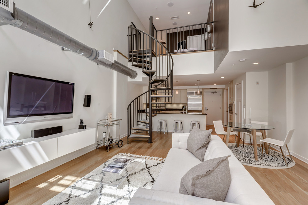 Imagen de sala de estar contemporánea sin chimenea con paredes blancas, suelo de madera en tonos medios y televisor colgado en la pared