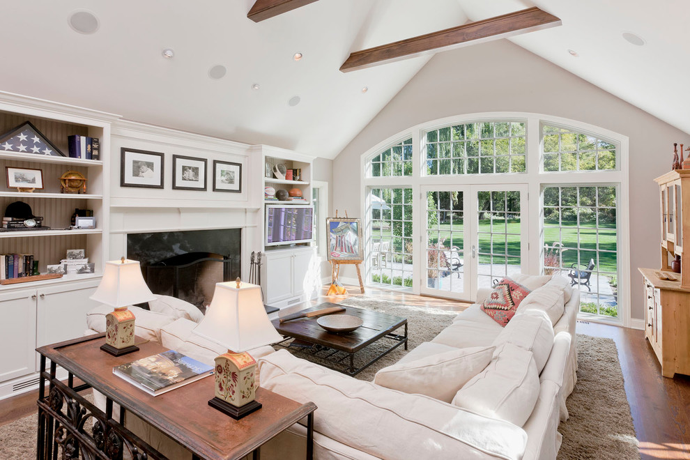 Foto de sala de estar clásica con paredes beige, suelo de madera en tonos medios, todas las chimeneas, marco de chimenea de piedra y alfombra