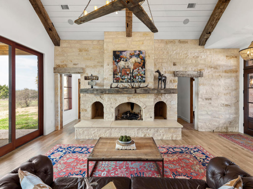 Design ideas for a country open plan games room in Austin with medium hardwood flooring, a stone fireplace surround and beige floors.