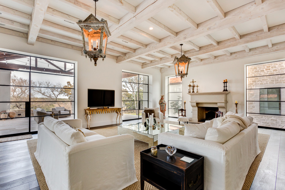 Mediterranes Wohnzimmer mit beiger Wandfarbe, hellem Holzboden, Kamin und freistehendem TV in Austin