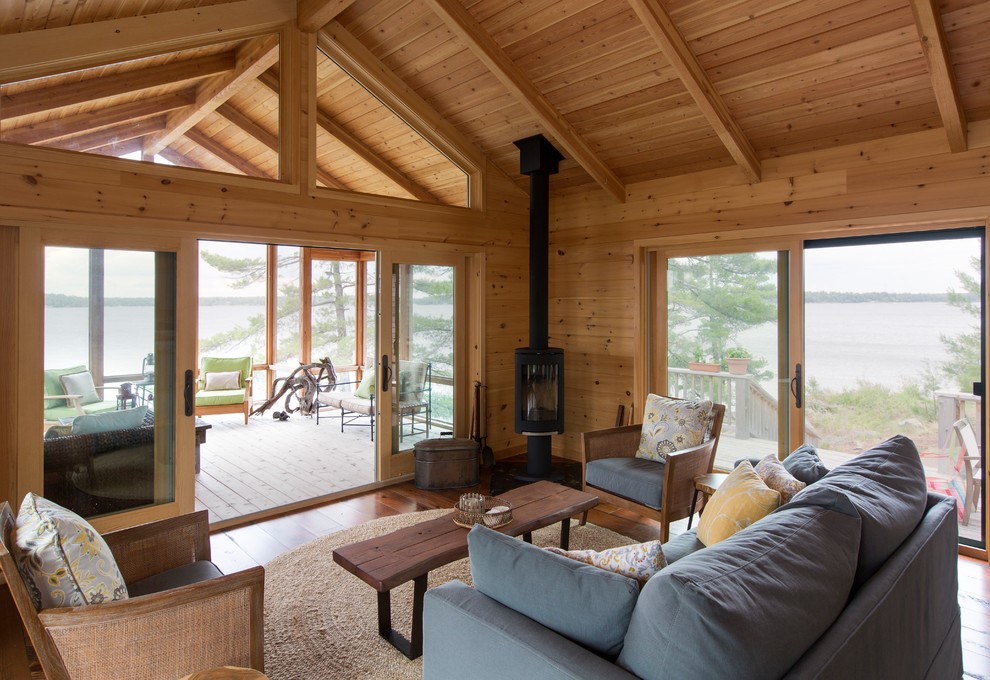 Immagine di un grande soggiorno rustico aperto con pareti marroni, pavimento in legno massello medio, stufa a legna, nessuna TV e pavimento marrone