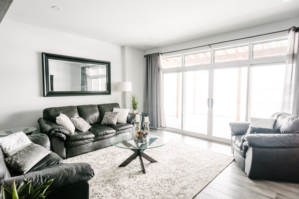 Aménagement d'une salle de séjour moderne de taille moyenne et fermée avec un mur blanc, un sol en bois brun, un téléviseur fixé au mur et un sol marron.