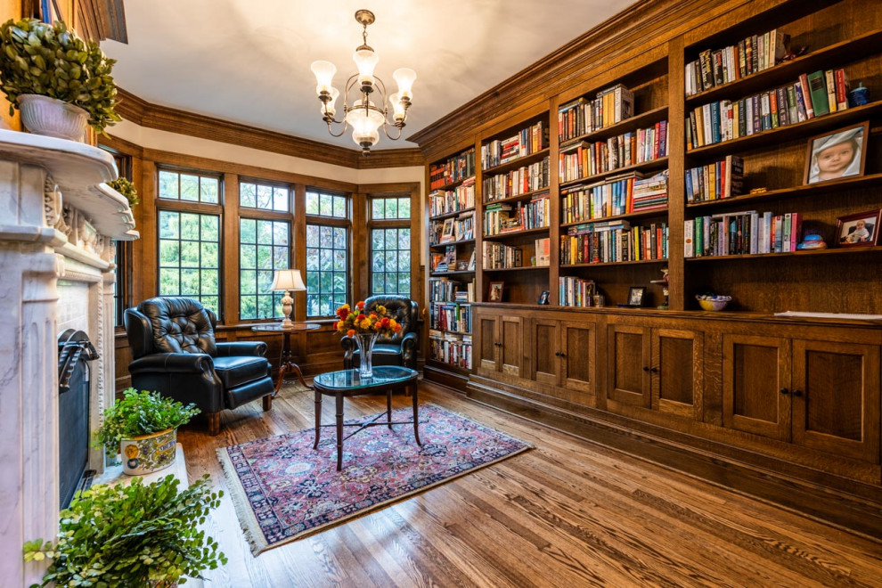 Diseño de sala de estar con biblioteca cerrada tradicional de tamaño medio con paredes beige, suelo de madera oscura, todas las chimeneas, marco de chimenea de madera, suelo marrón y boiserie