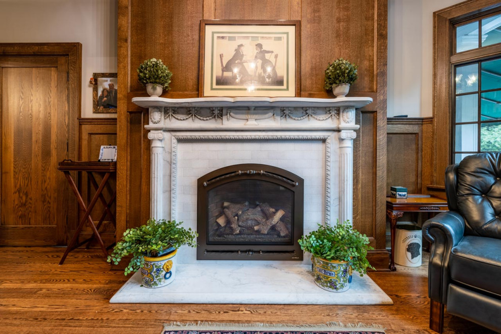クリーブランドにある中くらいなトラディショナルスタイルのおしゃれな独立型リビング (ライブラリー、ベージュの壁、濃色無垢フローリング、標準型暖炉、木材の暖炉まわり、茶色い床、羽目板の壁) の写真