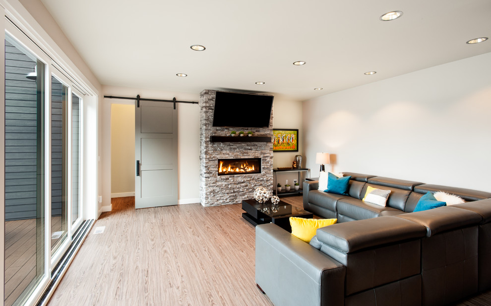 Mid-sized minimalist open concept brown floor family room photo in Seattle with gray walls, a standard fireplace, a stone fireplace and a wall-mounted tv