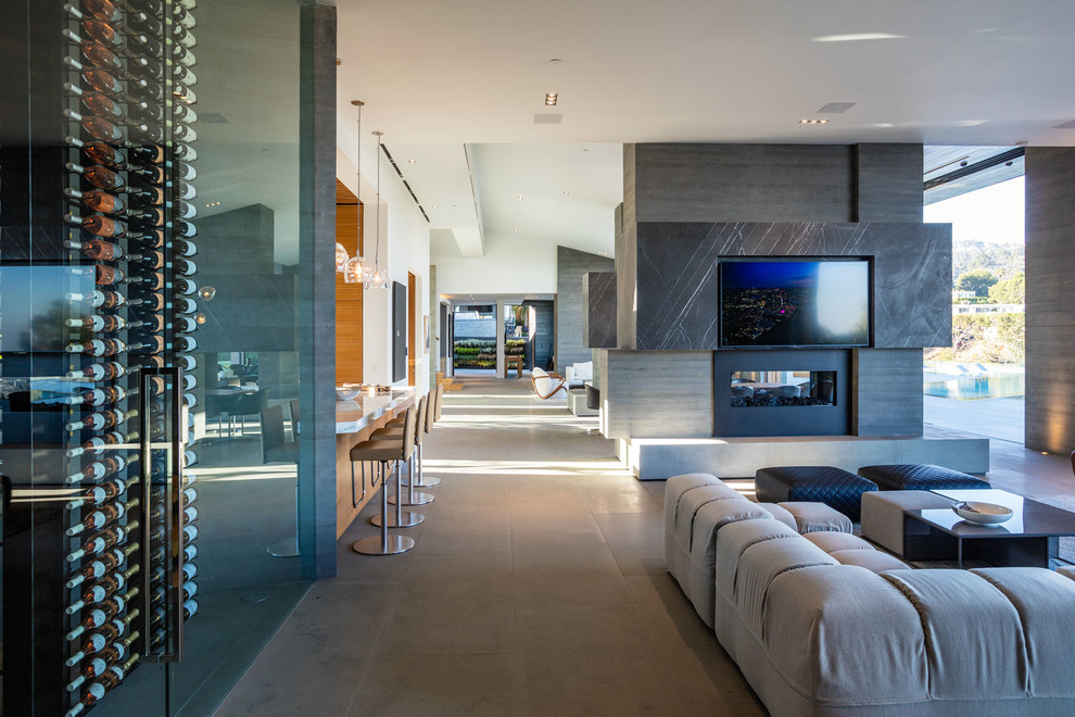 ロサンゼルスにある広いコンテンポラリースタイルのおしゃれなオープンリビング (ホームバー、白い壁、コンクリートの床、横長型暖炉、コンクリートの暖炉まわり、壁掛け型テレビ、グレーの床) の写真