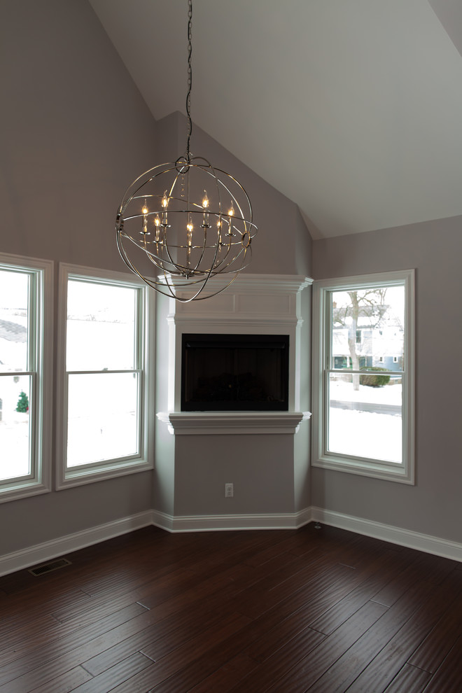 Imagen de sala de estar de estilo americano con paredes grises, suelo de madera oscura, pared multimedia y suelo marrón