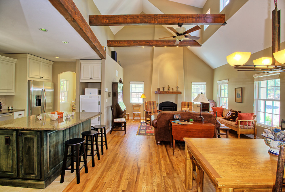 Cette photo montre une grande salle de séjour sud-ouest américain ouverte avec un mur beige, un sol en bois brun, aucun téléviseur, une cheminée standard et un manteau de cheminée en plâtre.
