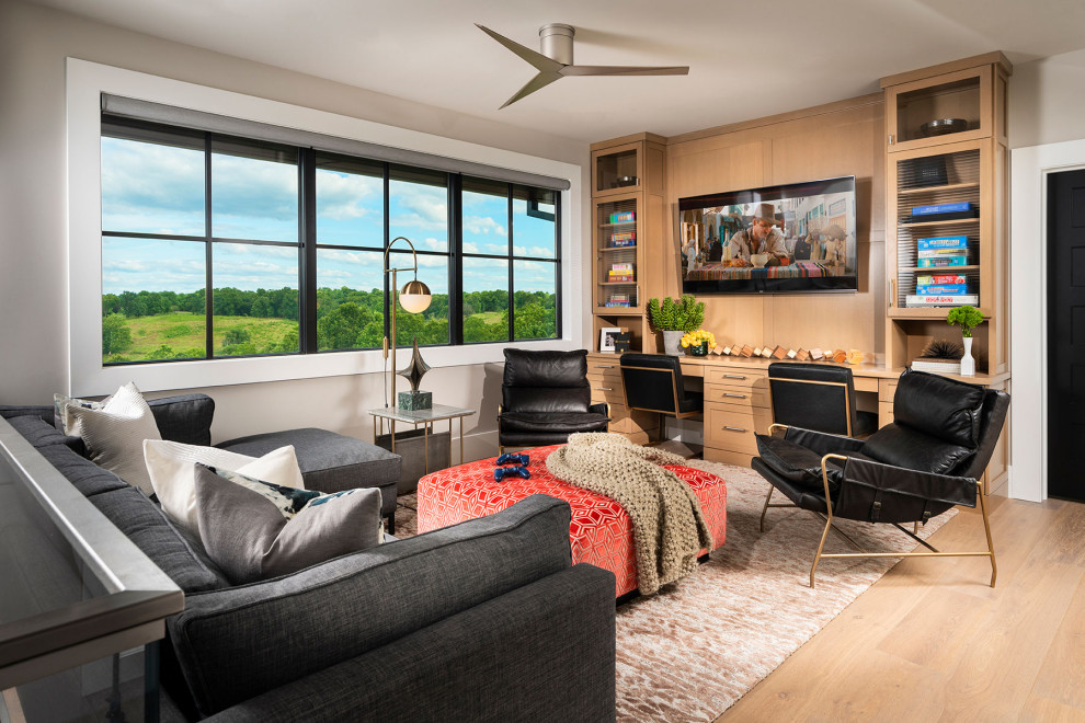 Immagine di un ampio soggiorno moderno aperto con sala giochi, pareti grigie, parquet chiaro, TV a parete e pavimento marrone