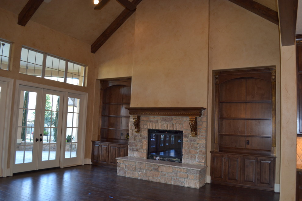 Imagen de sala de estar abierta tradicional extra grande con paredes beige, suelo de madera oscura, todas las chimeneas y marco de chimenea de piedra
