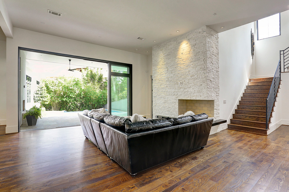 Inspiration pour une grande salle de séjour design ouverte avec un sol en bois brun, une cheminée d'angle et un manteau de cheminée en pierre.