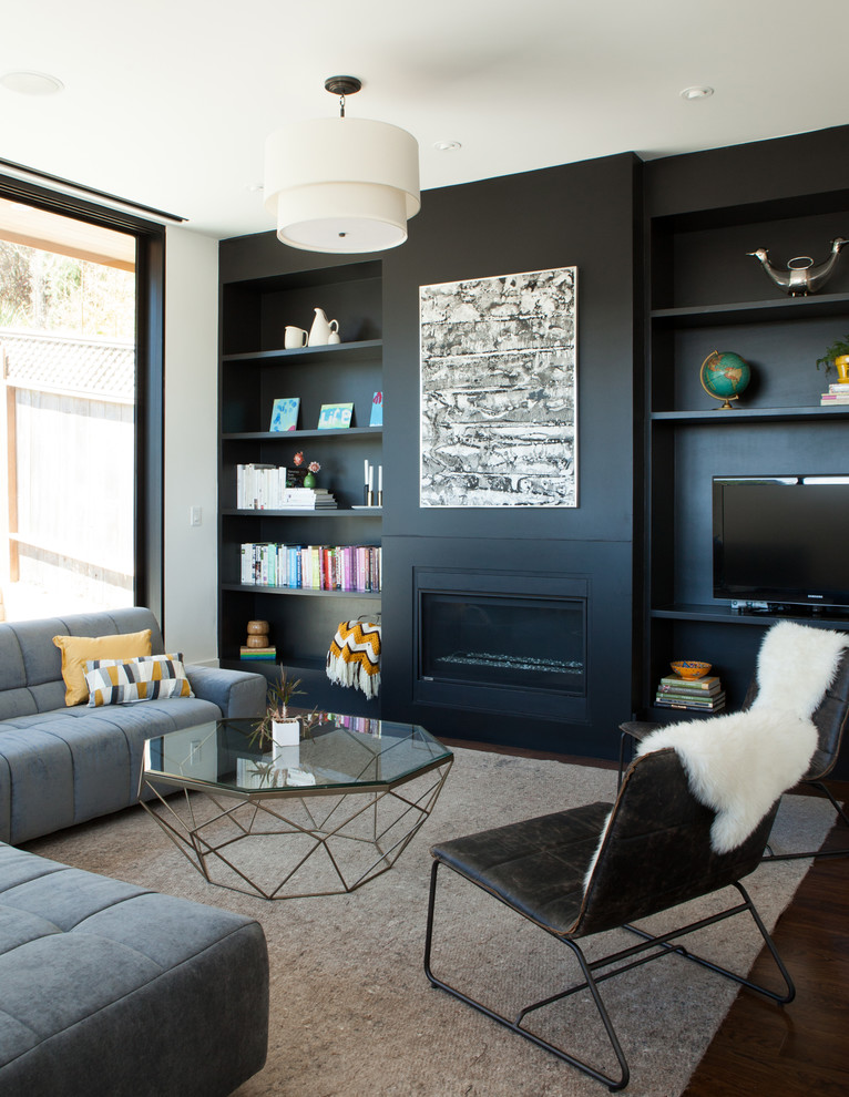 Ejemplo de sala de estar abierta actual de tamaño medio con paredes negras, todas las chimeneas, marco de chimenea de metal, pared multimedia, suelo de madera oscura y alfombra