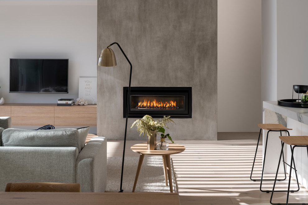 Inspiration for a small scandinavian open concept medium tone wood floor and brown floor family room remodel in Adelaide with white walls, a standard fireplace, a plaster fireplace and a wall-mounted tv