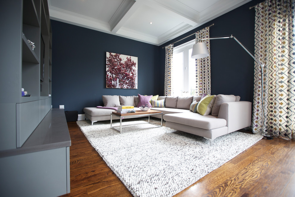 Ejemplo de sala de estar cerrada contemporánea grande sin chimenea con paredes azules, suelo de madera en tonos medios y televisor colgado en la pared
